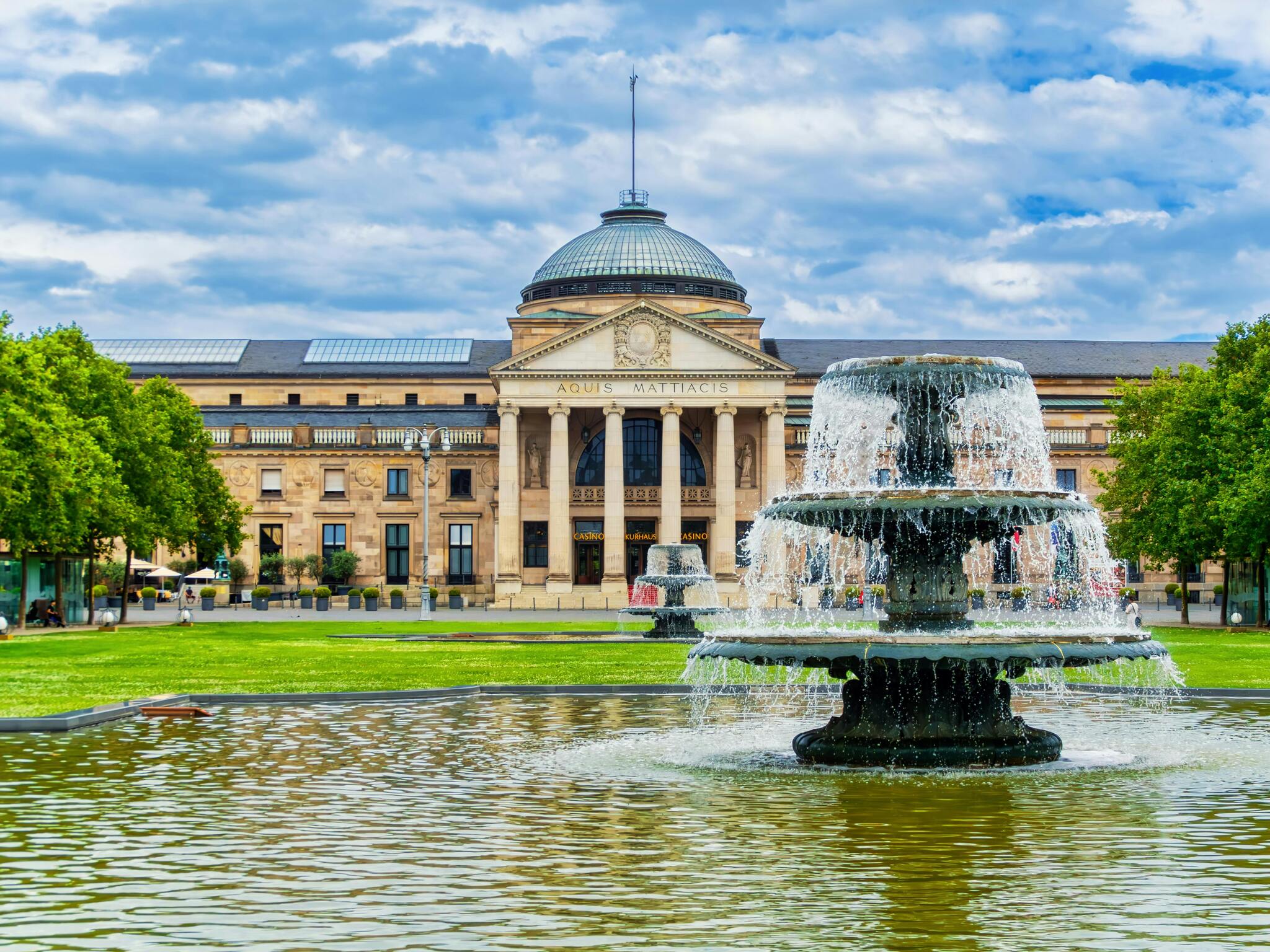 The Kurhaus in Wiesbaden with a fountain in the foreground under a bright sky