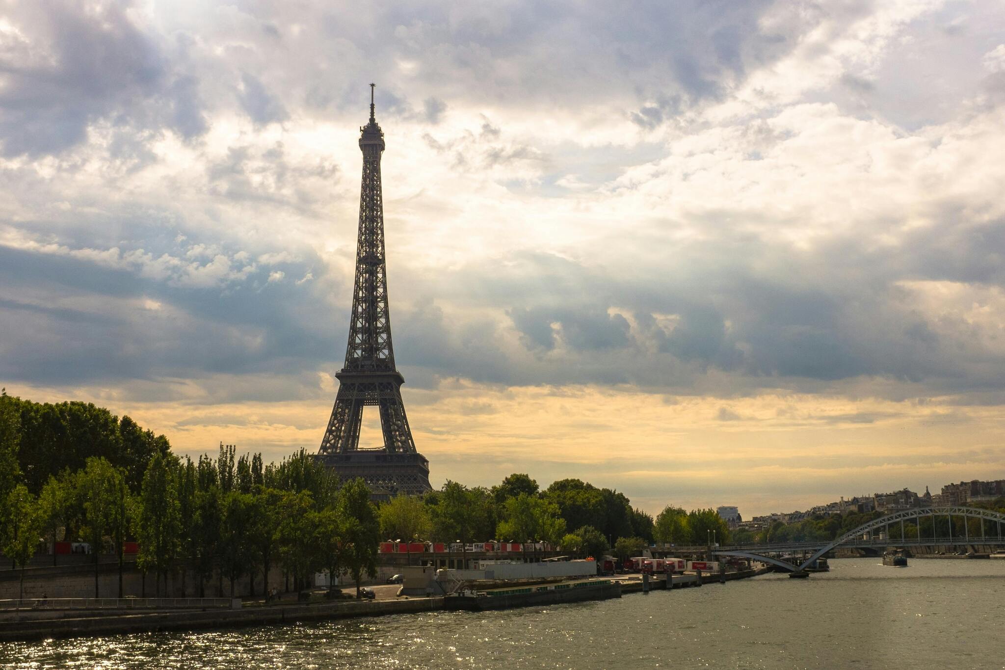 The Eiffel Tower at sunset above the River Seine and green trees