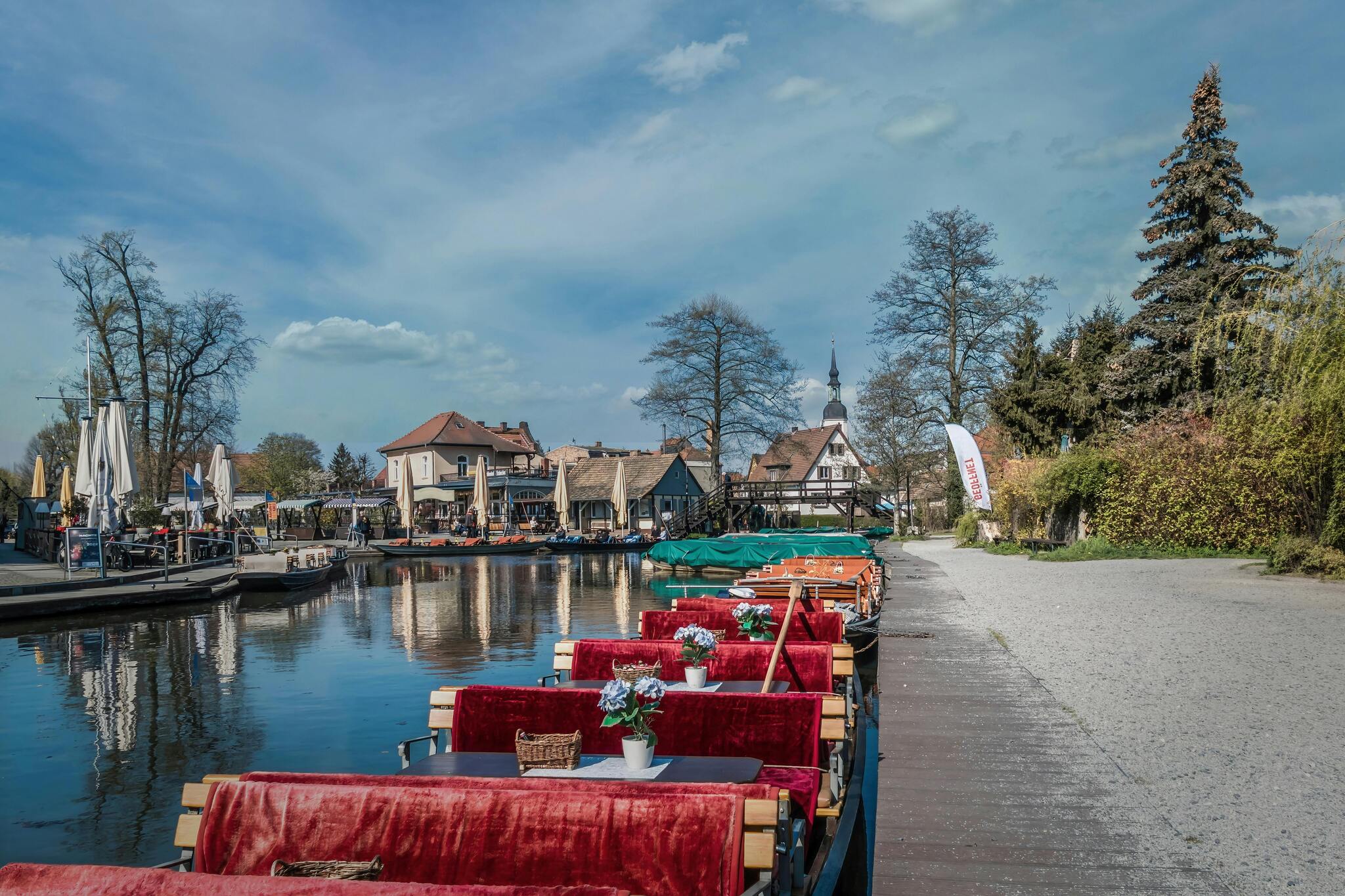 Tour boats lined up on a canal in the Spreewald, with traditional wooden houses